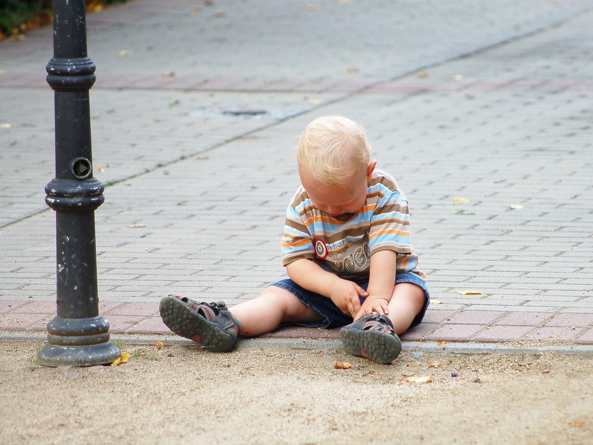 Chłopiec siedzi samotnie na chodniku