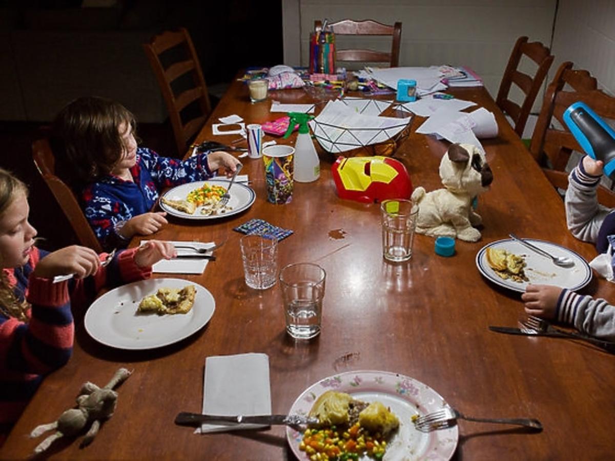 Dzieci jedzą kolację wśród zabawek
