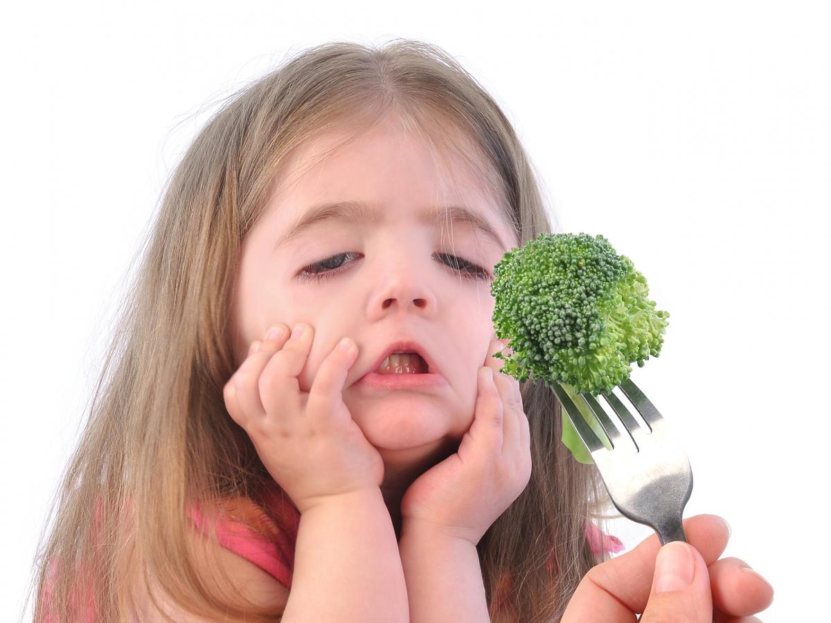 Dziewczynka robi śmieszną minę na widok brokułów