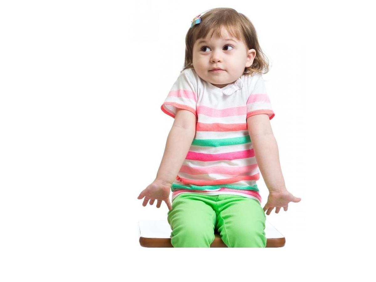 Dziewczynka siedzi na krześle i wzrusza ramionami