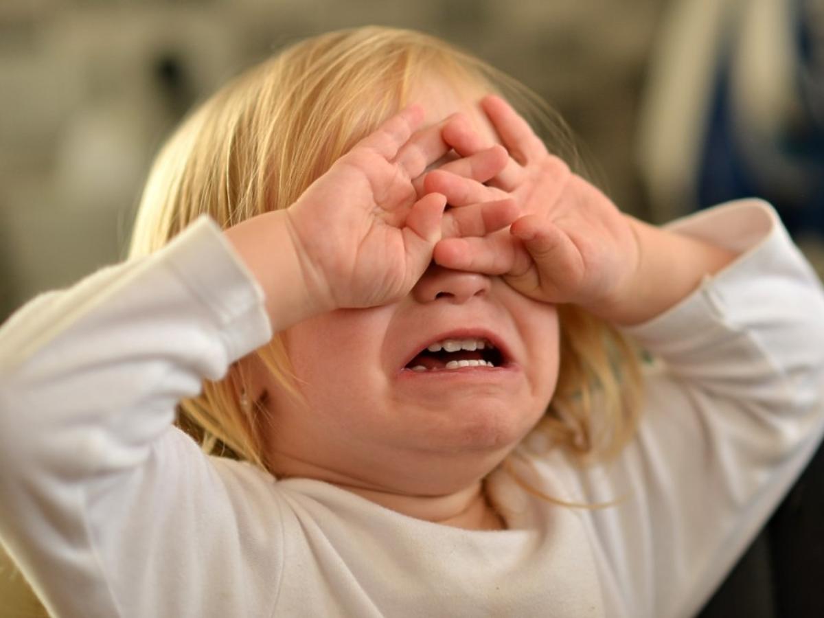 Małe dziecko płacze i zakrywa twarz rączkami