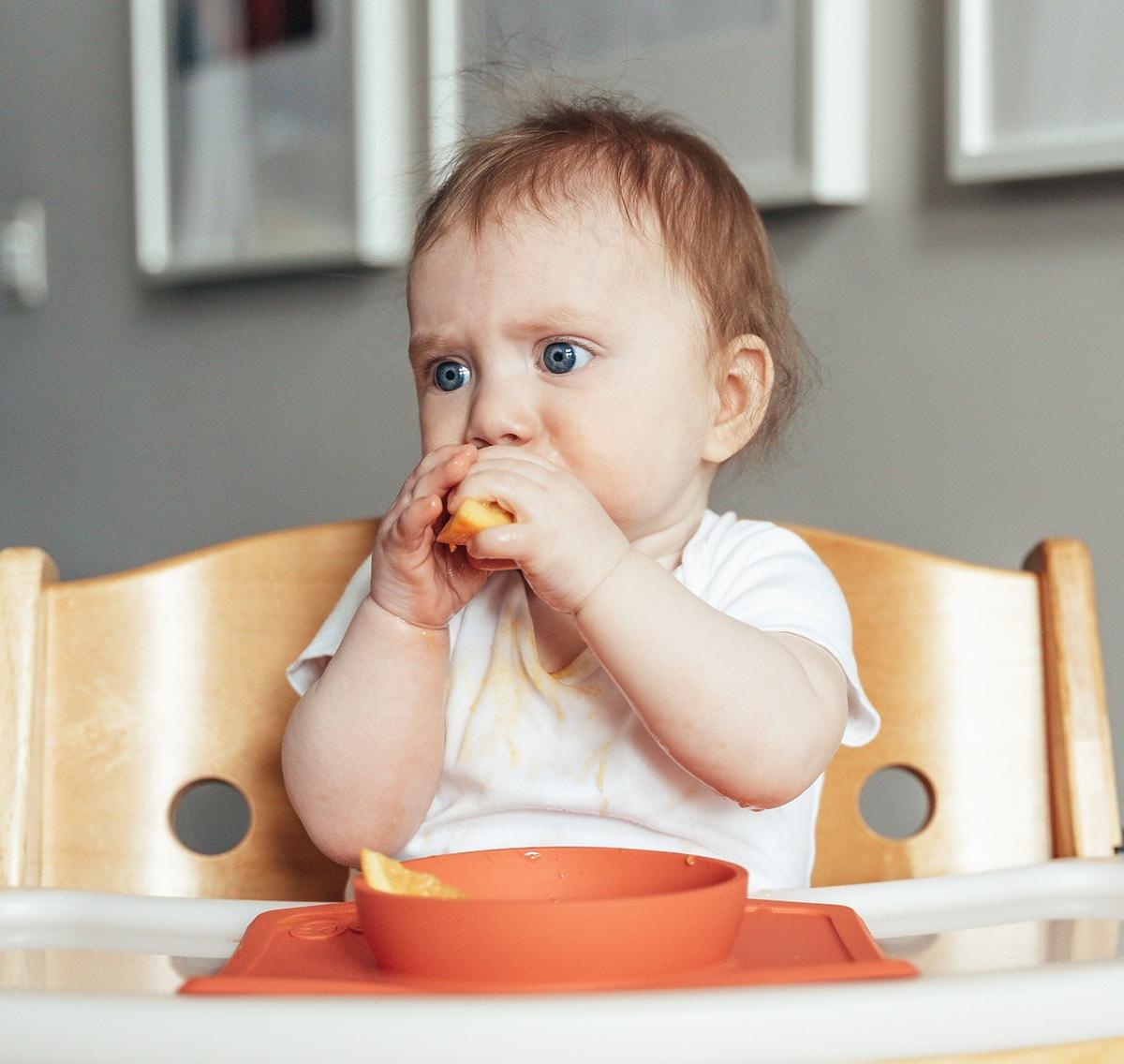 9-miesięczne dziecko je cząstki owocu zgodnie ze schematem rozszerzania diety
