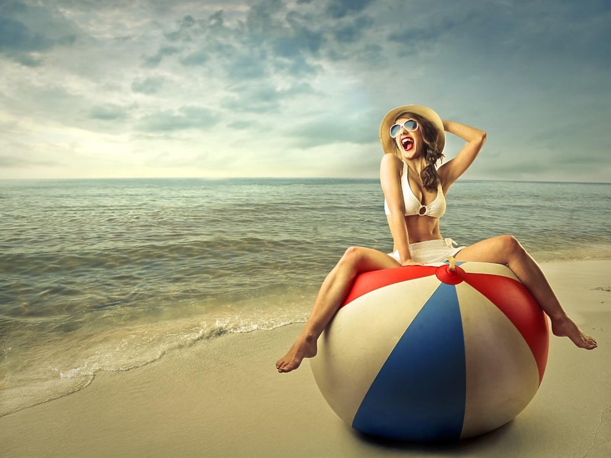 kobieta siedząca na olbrzymiej piłce plażowej