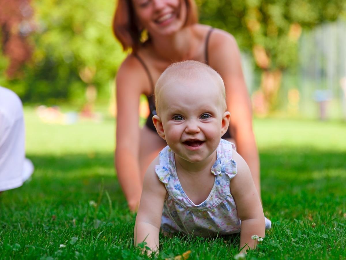 niemowlę 6 miesięczne raczkuje na trawie