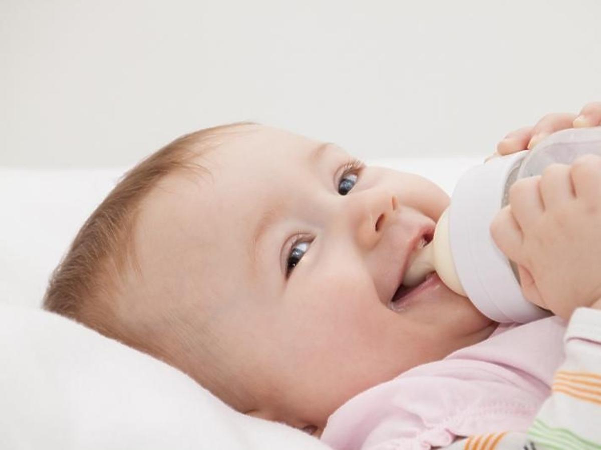 Uśmiechnięte niemowlę pije mleko z butelki